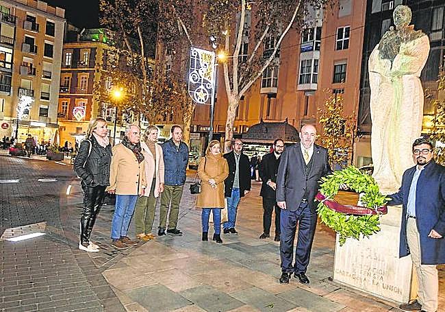 El presidente de la asociación belenista, Antonio Ferrer, y el edil Pablo Braquehais, junto a otros miembros, depositan una corona ante la escultura de San Francisco.