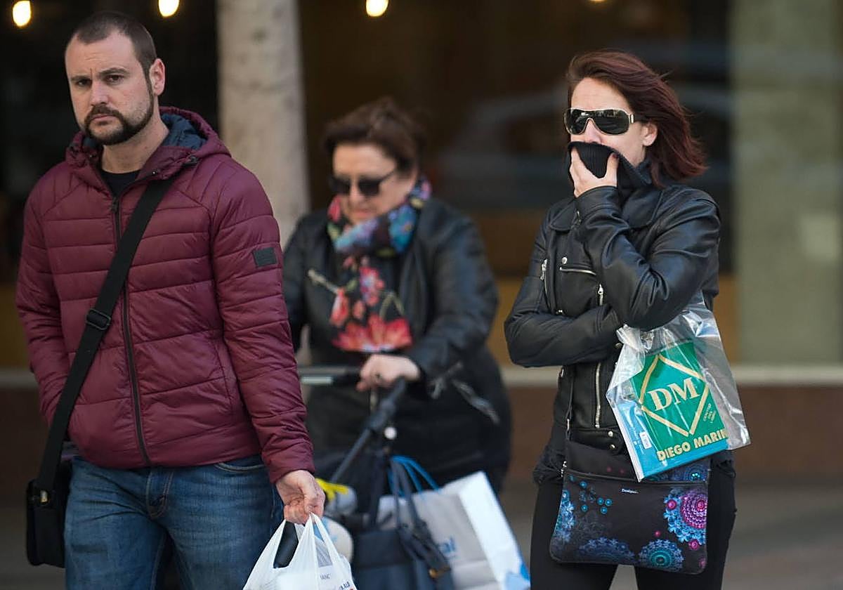 Viandantes se abrigan al caminar por la calle, en una imagen de archivo.