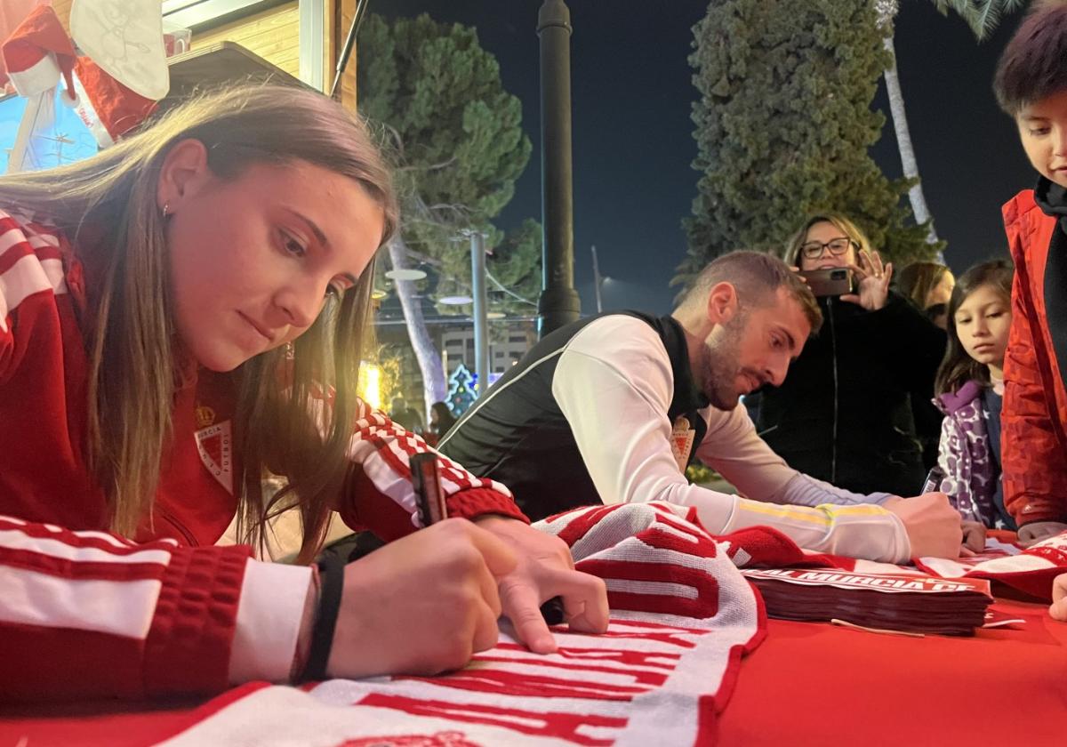 Andrea Lloret y Manu García, futbolistas del Murcia, firman a los aficionados en el gran árbol.