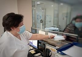 Una sanitaria ofrece una mascarilla a varios pacientes en un servicio de Urgencias.