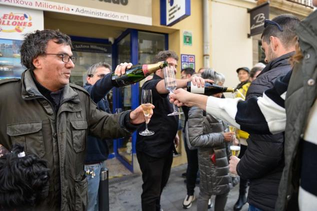 Agraciados con el primer premio del Sorteo Extraordinario de la Lotería del Niño correspondiente al número 89.603 celebran su suerte en la administración 1 situada en la calle Pintor Enric Serra, en L’Escala, Girona, Catalunya (España).