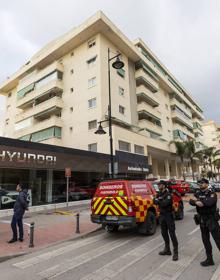 Imagen secundaria 2 - En la imagen superior, los bomberos en la terraza del piso donde comenzó el fuego; debajo, vista de la fachada del edificio de Fuengirola en la que se observa como el incendio terminó dañando parte de los pisos superiores; por último, varios policías vigilan los acceso al lugar de los hechos.