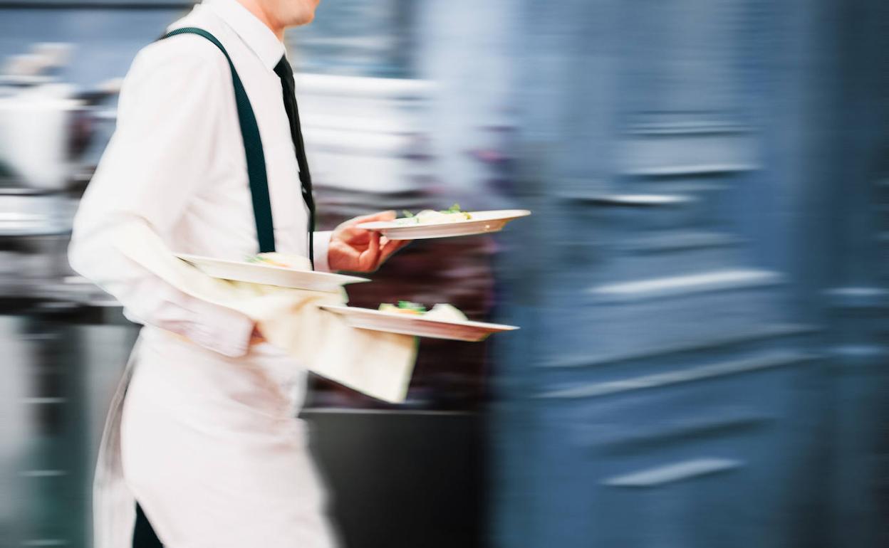 Imagen de archivo de un camarero llevando varios platos.