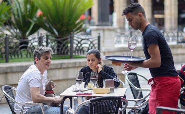 A waiter with some customers on the terrace of a bar, in a file image.
