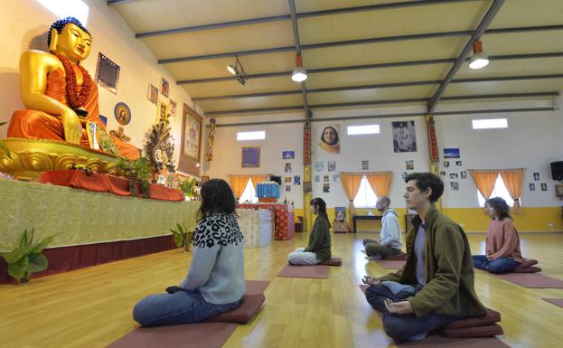 Varios miembros de Mahasandhi meditan en la sala Gompa ante un gran Buda.