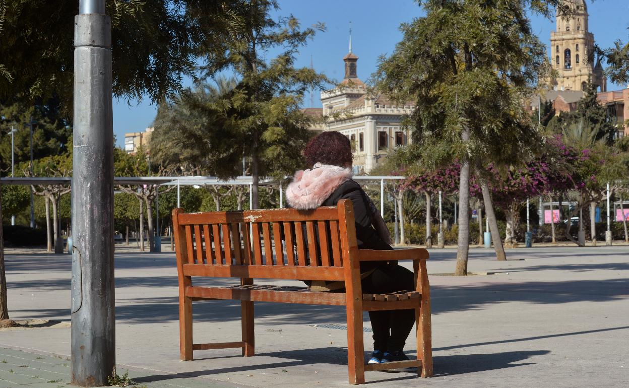 Isabel, usuaria de Cruz Roja, sentada en una banco de un parque de Murcia.