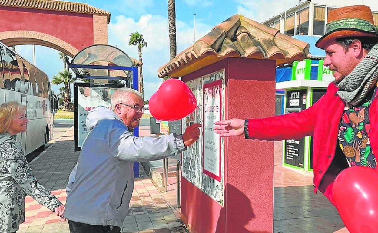 Un animador social reparte globos con formas de corazón.