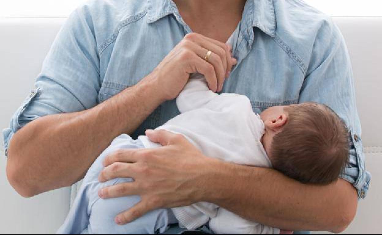 Un padre con su bebé en brazos.