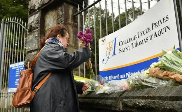 A woman places a bouquet of flowers at the entrance of the center where teacher Agnès Lassalle was fatally stabbed on Wednesday