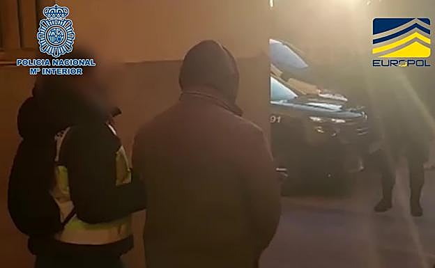 Un agente escolta a uno de los detenidos.