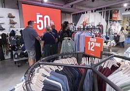 Varios clientes hacen cola para pagar en una tienda del centro, mientras que otros echan un vistazo a la ropa en oferta, ayer.