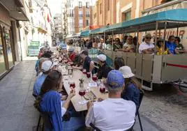 Visitantes toman una marinera con un tinto de verano en un bar de la calle del Aire, frente a Santa María de Gracia, mientras otro grupo pasea en el tren turístico.