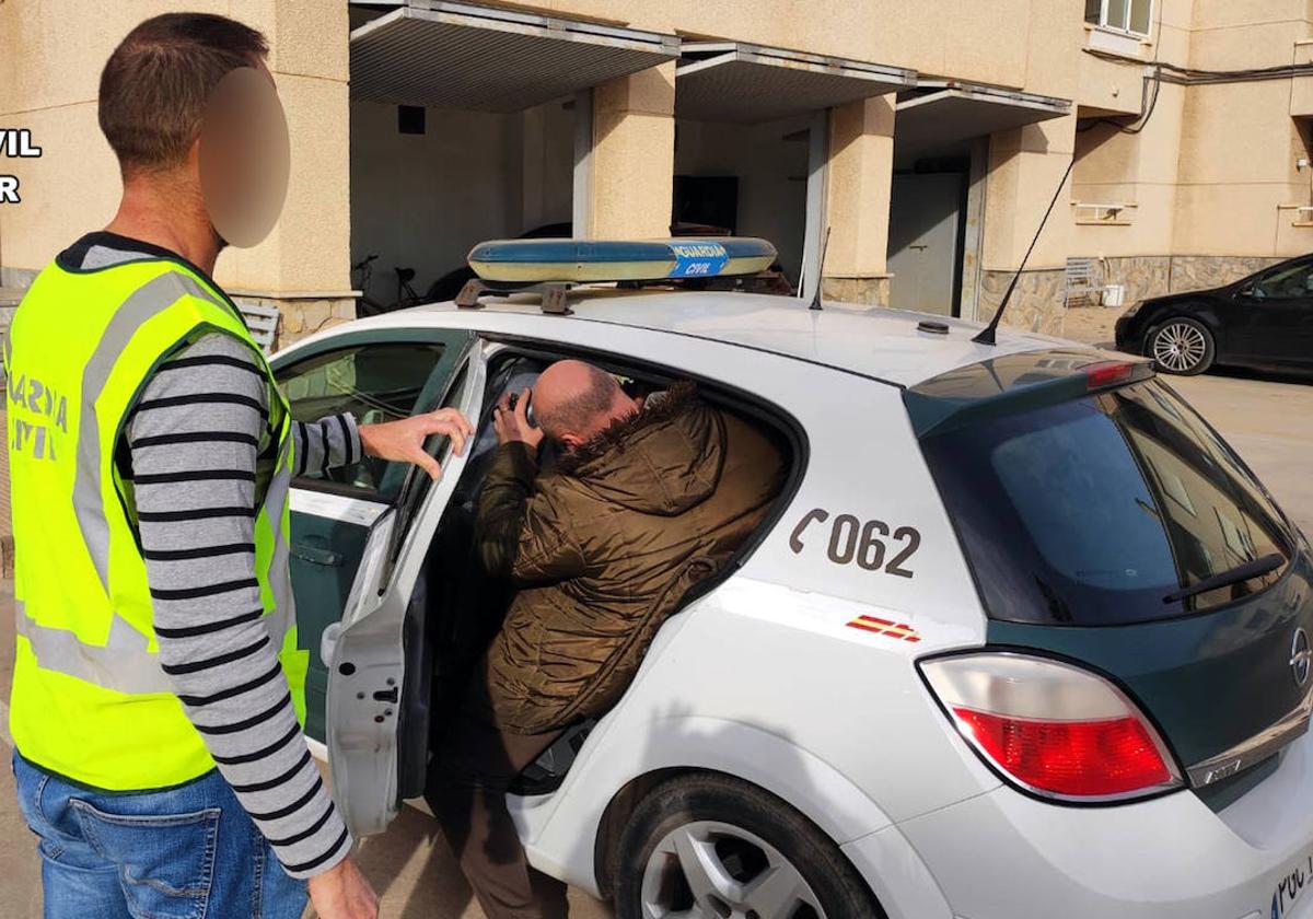 Un Guardia Civil introduce a un integrante de la banda detenida en el coche.