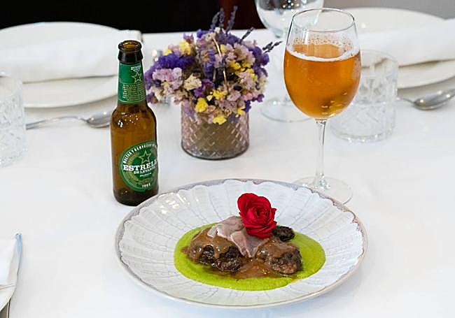 Plato de carrillada de chato murciano sobre una crema de guisantes y un velo de tocino, junto a una cerveza Estrella de Levante.