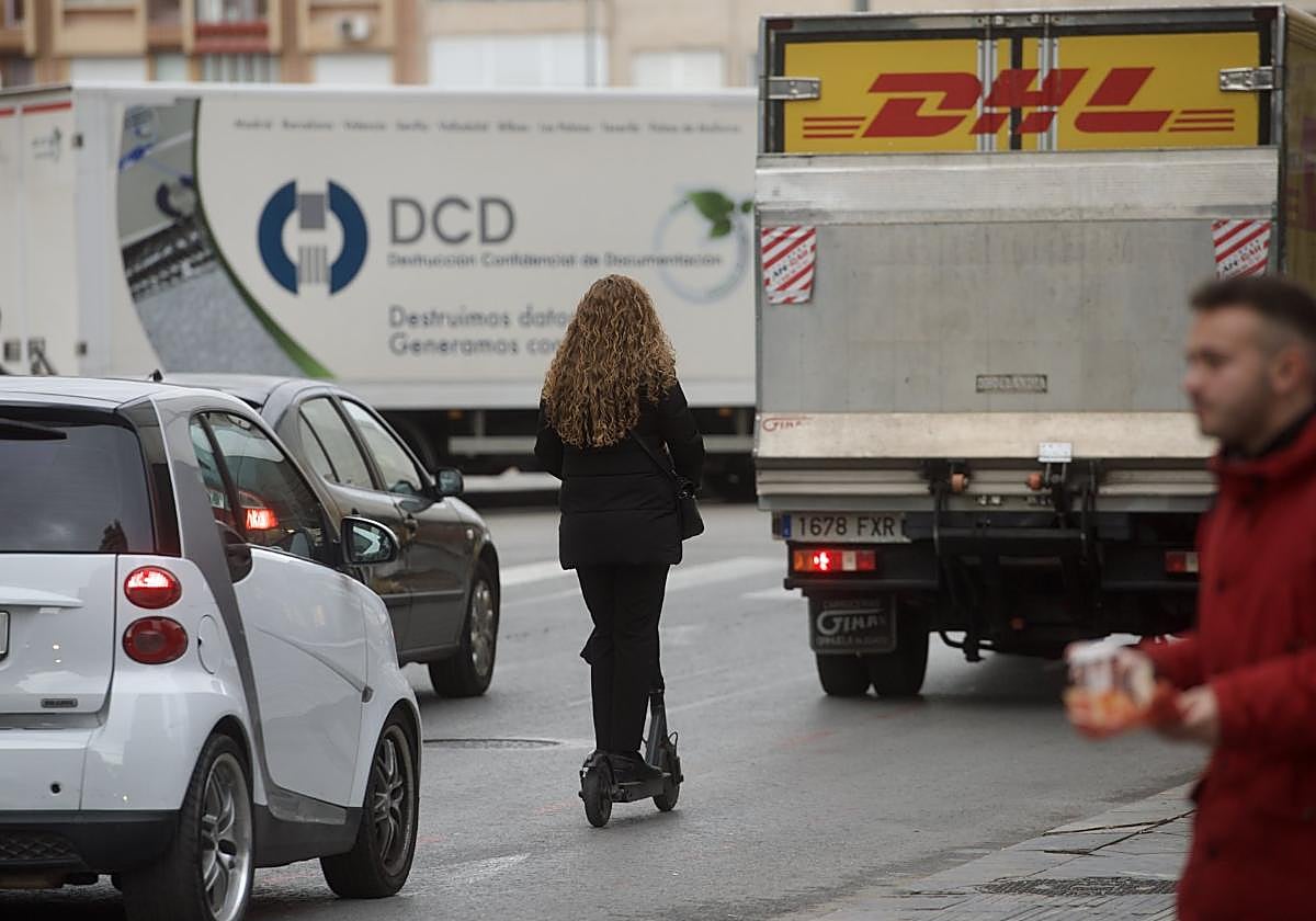 Una mujer circula con un patinete por la carretera.