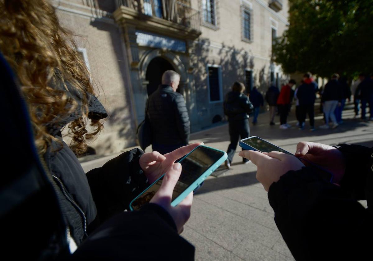 Dos alumnas revisan sus teléfonos en la puerta de su instituto en el centro de Murcia.