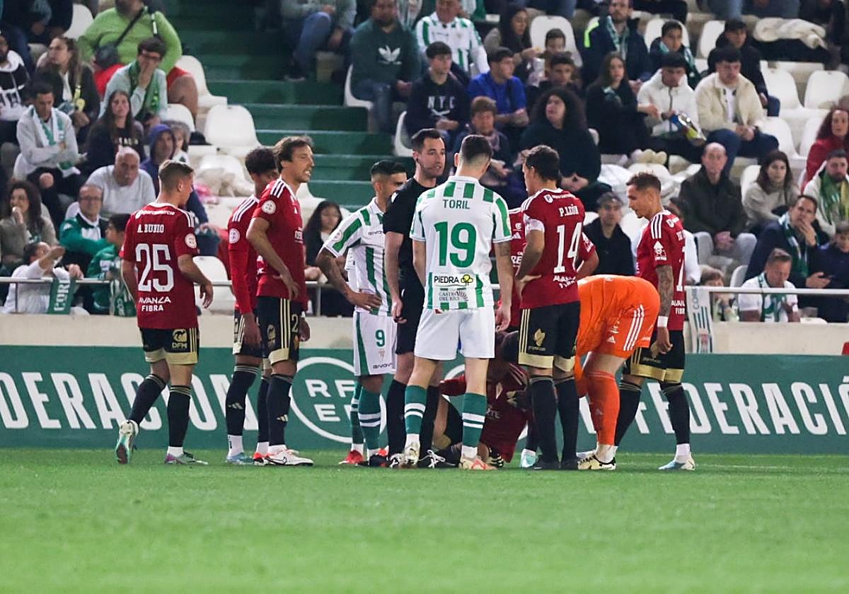 Los jugadores del Real Murcia y el Cordoba rodean, en el choque del pasado sábado, a un Larrea atendido por los médicos del club grana en el Nuevo Arcángel.