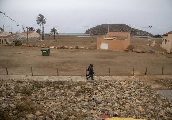 Dos hombres caminan por el entorno de la playa de la Isla, en Mazarrón, cerca de varias viviendas, este viernes por la tarde.