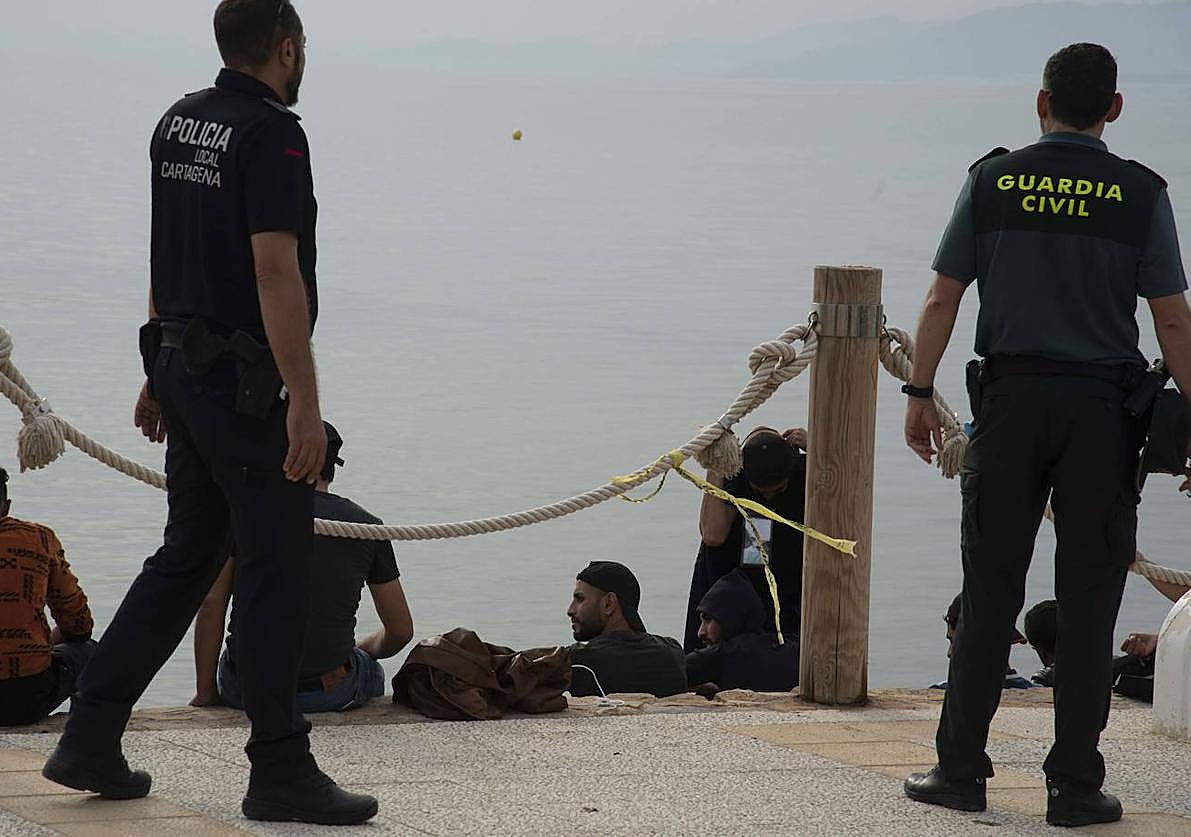 Agentes vigilan a inmigrantes recién llegados a Cartagena en patera en una imagen de archivo.