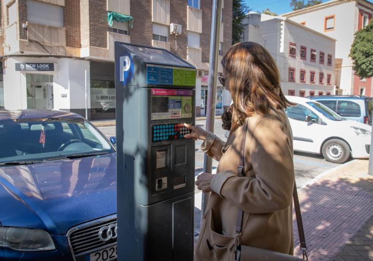 Una mujer saca un tíquet de un parquímetro de la plaza San Sebastián.