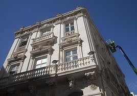 Obreros en una plataforma realizan trabajos en la fachada de la Casa Pedreño.