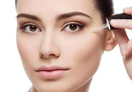 Una chica aplicándose un sérum en la cara.