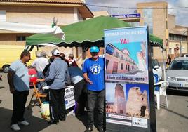 Un vecino muestra un cartel delante de una mesa donde se informa de la intención de crear una de Entidad Local Menor, en El Algar.