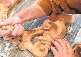 Un maestro artesano trabaja sobre una pieza de madera ornamental, en imagen de archivo.
