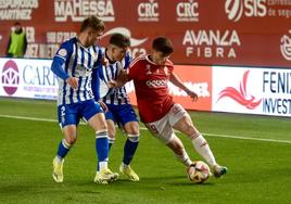 Juanmi Carrión, lateral izquierdo del Real Murcia, entre dos jugadores del Recreativo.