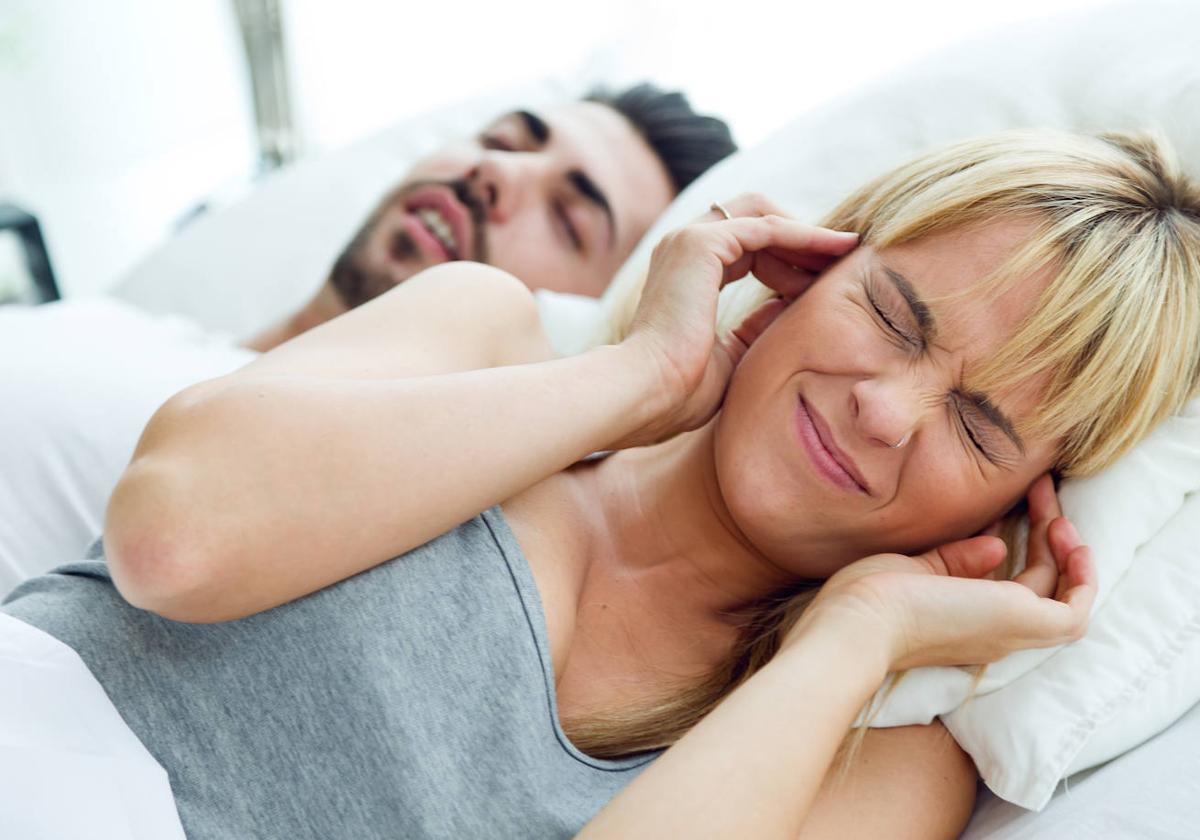 Un hombre roncando y una mujer intentando dormir.