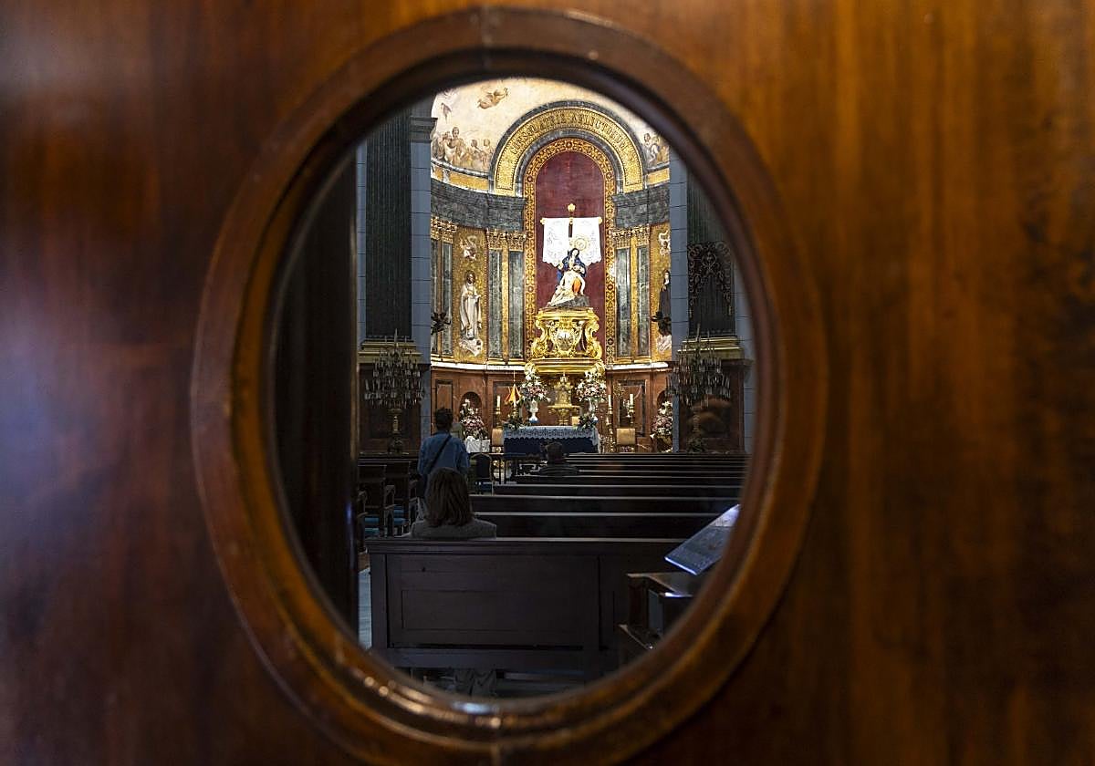 La Virgen de la Caridad, en la víspera de su día, vista a través de un ojo de buey de la puerta de su basílica.