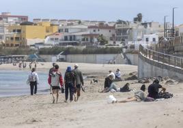 Turistas pasean este jueves por la playa, en Cabo de Palos, en una jornada protagonizada por el viento y las nubes.