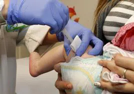 Una sanitaria administra una vacuna a un bebé.