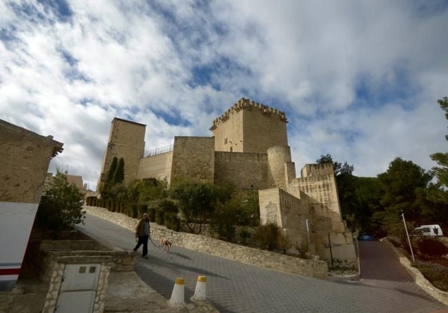 Un vecino pasea con su perro junto al castillo de Moratalla.