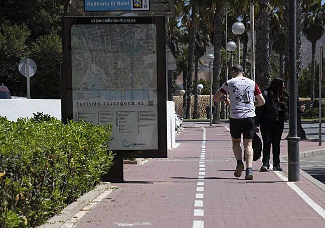 Un corredor y un peatón se cruzan en el carril-acera del Paseo Alfonso XII.