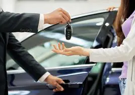Un comercial entrega las llaves de un coche a una clienta.