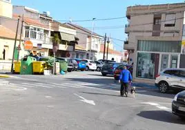 Un vecino pasea su perro junto a la plaza de la Inmaculada, con los contenedores de basura.