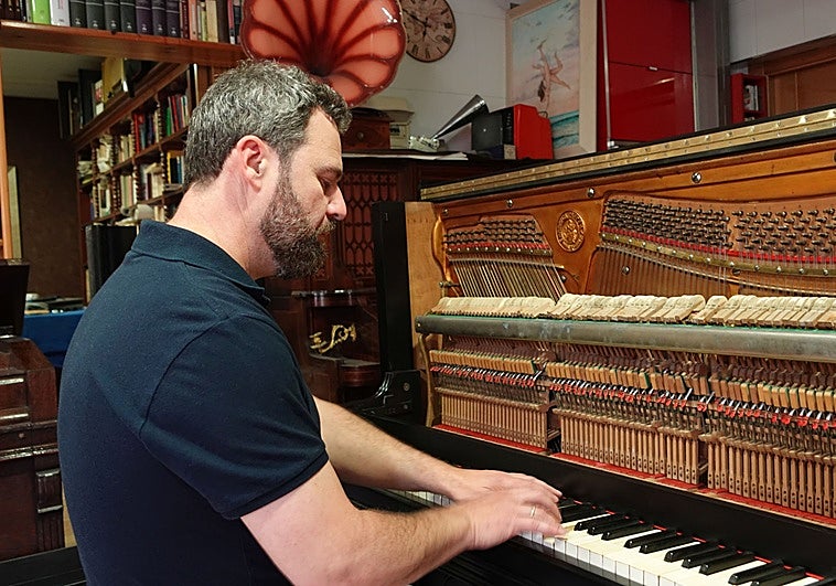 Víctor Javier Martínez prueba el sonido del piano del Casino, en su taller.