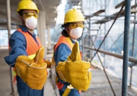 Dos empleados, ataviados con todos los elementos de seguridad laboral.