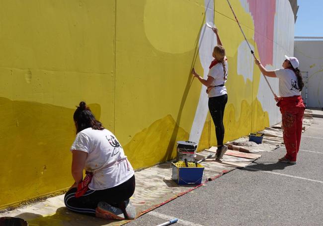 Las integrantes de Triple M Artists trabajan en el mural.