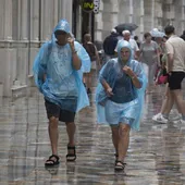 Unas personas se cubren con un chubasquero en un día de lluvia en Cartagena.