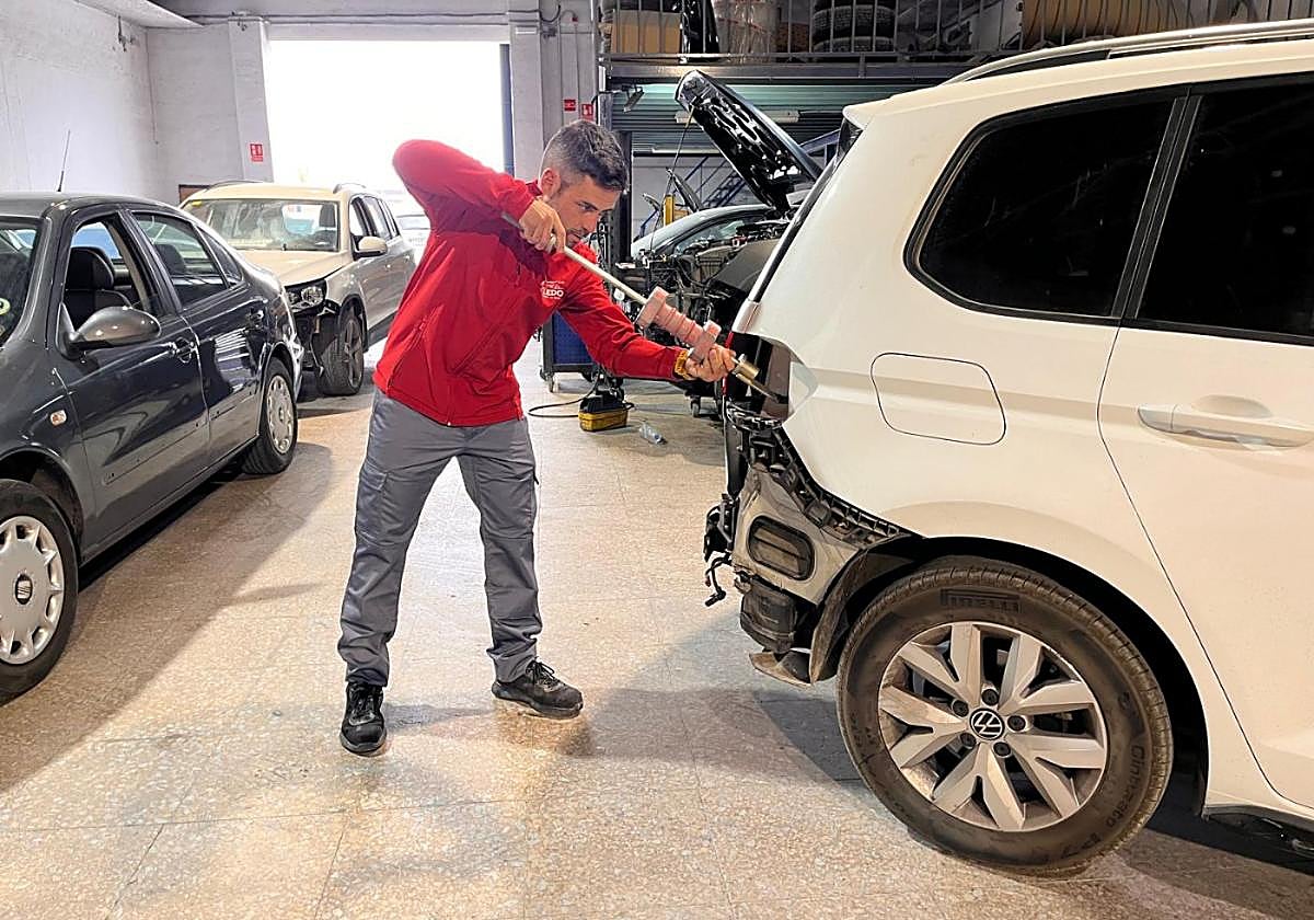 Juanfran Aledo trabaja en la reparación de un vehículo en las instalaciones de su taller de chapa y pintura en Alhama de Murcia.
