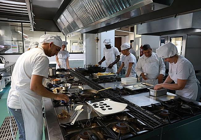 Antonio Amador (2º d) da instrucciones a los alumnos en la cocina de la Escuela de Hostelería durante la preparación de un plato.
