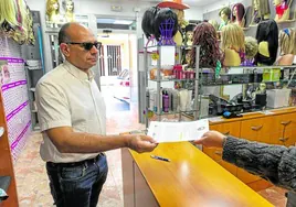 Un vecino entrega su firma para exigir la restitución del servicio entre Cartagena y Madrid en la tienda Comercial Rubio.
