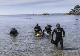 Un grupo de alumnos sale del agua tras una práctica en Cala del Muerto, en Cabo de Palos, mientras un compañeros, al fondo, sigue sumergido.