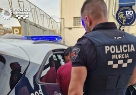 La Policía Local de Murcia meten al detenido en el coche.