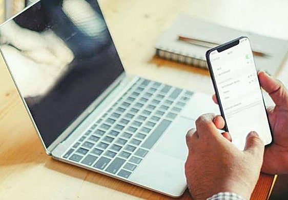 Una persona conectada a internet desde su portátil y desde su móvil. Imagen de archivo.