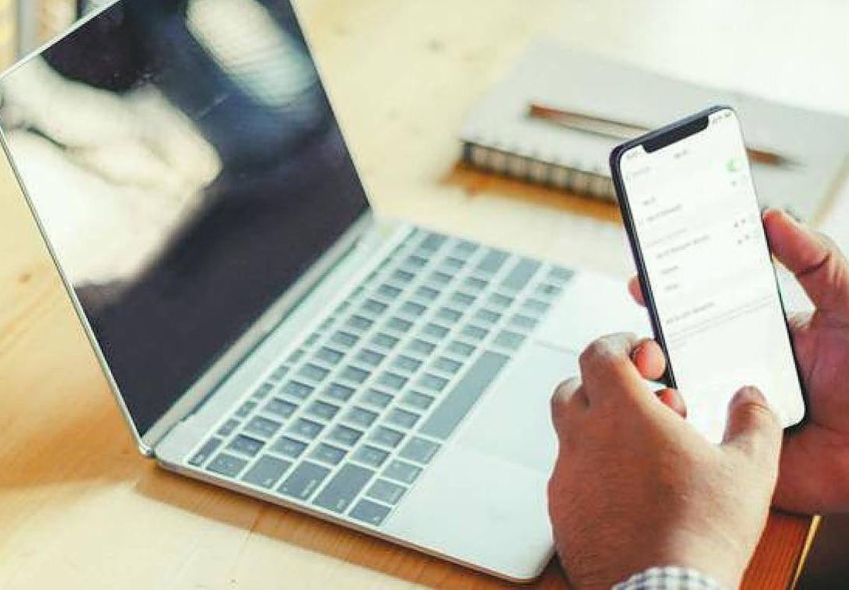 Una persona conectada a internet desde su portátil y desde su móvil. Imagen de archivo.