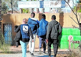 Un grupo de inmigrantes entra al campamento del Hospital Naval, junto a una empleada de Accem, que se encarga de su gestión.