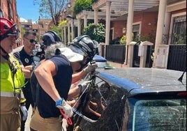 Efectivos de bomberos rescatan a un niño del interior del coche.